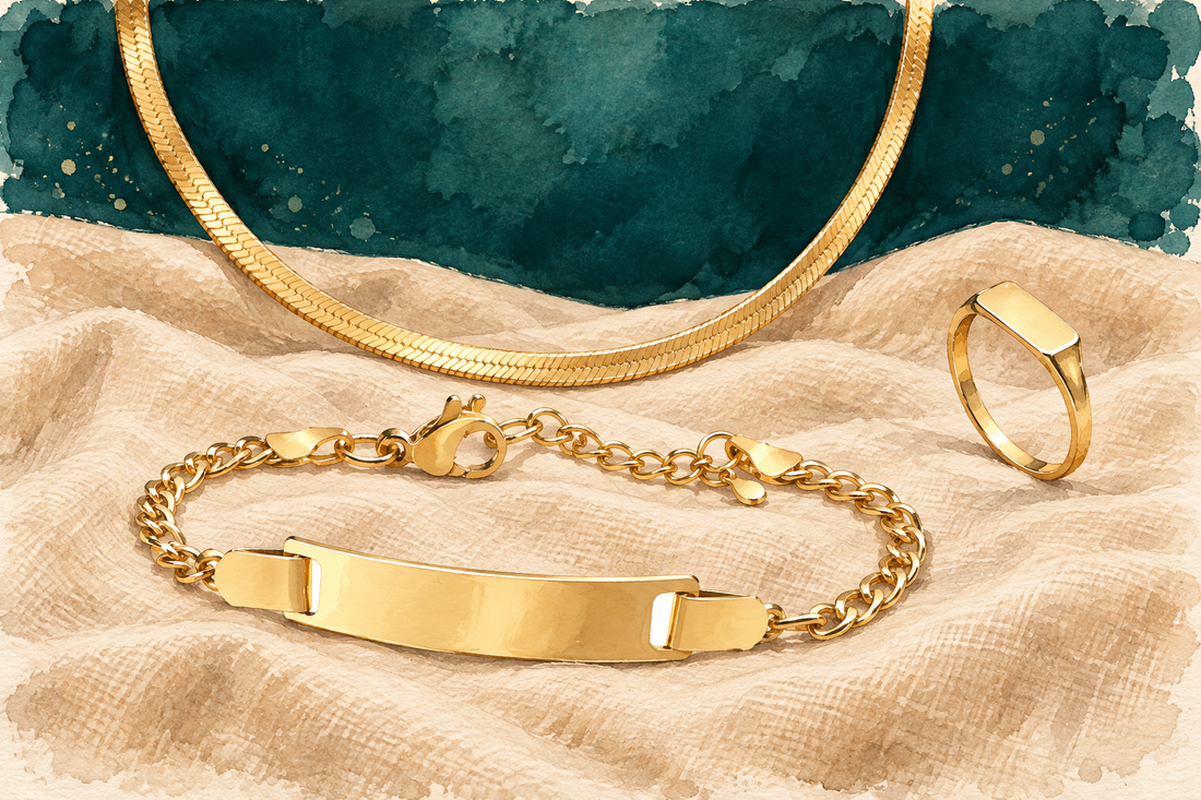 Ilustração em aquarela de joias de aço inox dourado: pulseira com placa, corrente snake e anel retangular sobre linho
